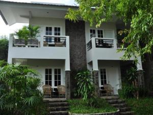 a white house with chairs and trees at Hotel Minahasa in Manado