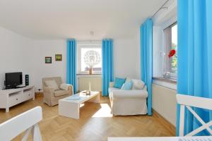 een woonkamer met blauwe gordijnen, een bank en een tv bij Ferienwohnung Hornfisch in Breege