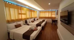 een hotelkamer met drie bedden en een televisie bij Hotel Asuncion in Laoag +29 foto's