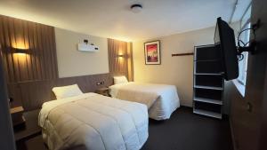 a hotel room with two beds and a television at Hotel Posada de Belén in Espinar