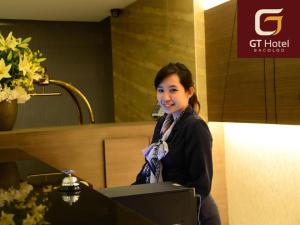 Una mujer parada en un escritorio en una habitación en GT Hotel Bacolod, en Bacolod