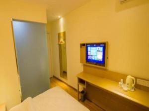 ein Schlafzimmer mit einem TV an der Wand und einem Bett in der Unterkunft 7 Days Inn Ya'an Langqiao Pedestrian Street Center in Ya'an