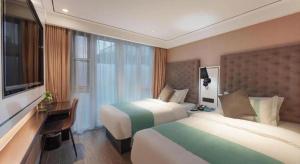 a hotel room with two beds and a desk and a television at Xana Lite Beijing Sidaokou Dazhong Temple Metro Station Branch in Beijing
