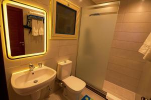 un bagno con lavandino, water e specchio di THree PYramiDs & SPhinX HoTeL a Il Cairo Altre 37 foto