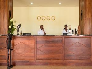two men are sitting at a counter in a bar at Raphael's Hotel in Pemba