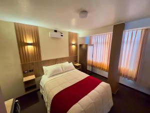 a bedroom with a bed with a red and white blanket at Hotel Posada de Belén in Espinar +14 photos