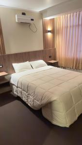 a bedroom with a large white bed with a air conditioner at Hotel Posada de Belén in Espinar