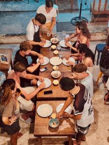Eine Gruppe von Menschen sitzt um einen Tisch und isst. in der Unterkunft Yes Surf Siargao in General Luna