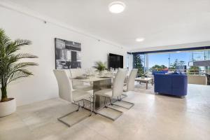 a dining room with a table and white chairs at Beachfront Escape Zenith - Ocean Views, Pool, Spa in Gold Coast