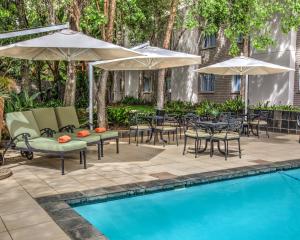 een patio met tafels en parasols naast een zwembad bij City Lodge Hotel Bryanston in Johannesburg