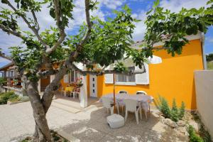 a patio with a table and chairs in front of a yellow house at Apartment Marta in Ražanac