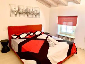 a bedroom with a bed with a red and black comforter at SteCla's House Garda in Garda