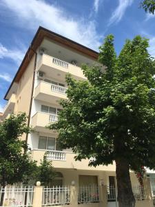 un edificio blanco alto con un árbol delante de él en Borko Guest House en Primorsko