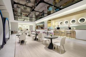 a restaurant with tables and chairs and a counter at Atour X Hotel Qingdao Shilaoren Beach Exhibition Center Metro Station in Qingdao