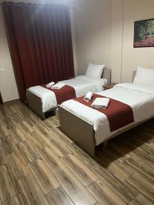 two beds in a room with wooden floors at Eljos Hotel in Tirana
