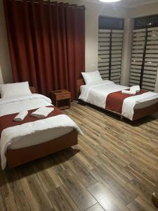 two beds in a room with wooden flooring at Eljos Hotel in Tirana +2 photos