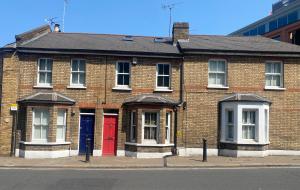 a brick building with red doors on a street at Three Bedroom House in Central Richmond in Richmond upon Thames