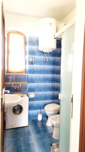 Un baño con azulejos azules, inodoro y lavabo. en Le Pleiadi - Casa Casoni, en Marcelli