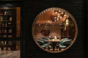 a round mirror on a wall with a table and chairs at Tomeet Hotel in Meizhou