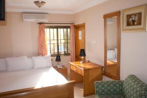a bedroom with a bed and a desk and a mirror at Eastgate Hotel in Accra