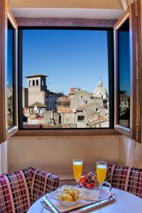 stół z talerzem jedzenia i dwiema szklankami soku pomarańczowego w obiekcie Navona Palace Luxury Inn w Rzymie