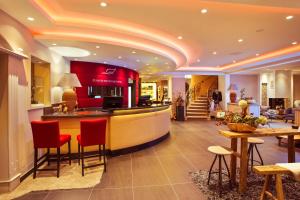 una hall con bar con sedie rosse di Romantischer Winkel RoLigio & Wellness Resort a Bad Sachsa