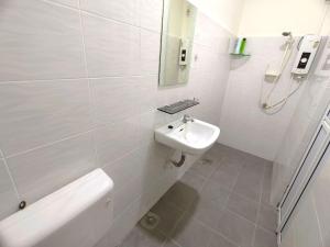 a white bathroom with a sink and a toilet at Lighthouse Tmn Intan 6pax Water Dispenser Neflix Target in Kluang +12 photos