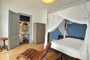 a bedroom with a canopy bed and a chair at Hotel Le Rayon Vert in Étretat