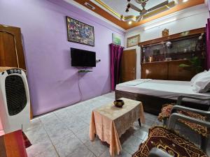 a bedroom with purple walls and a bed and a tv at Pavitram Guest House in Ujjain