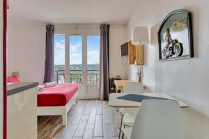 a small room with a bed and a table and a room with a balcony at Le Léon 15 charmant studio avec balcon vue mer situé à Dieppe in Dieppe