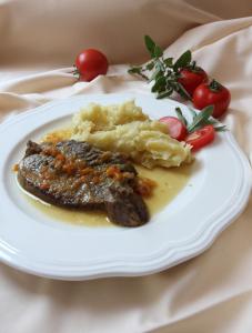 a plate of food with meat and mashed potatoes and tomatoes at Turistična Kmetija Logar in Grahovo