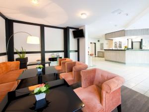 a living room with orange chairs and a table at ACHAT Hotel Frankfurt Airport in Langen