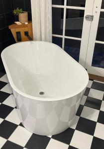 a bath tub in a bathroom with a black and white floor at Eden Niu in Eden