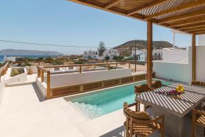 a patio with a table and a swimming pool at Lavea Milos Boutique Suites in Pollonia