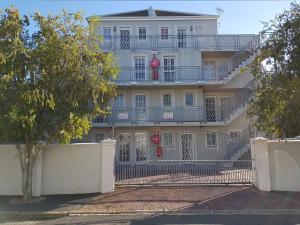 un gran edificio blanco con balcón y un árbol en Bradclin Sport Newlands, en Ciudad del Cabo