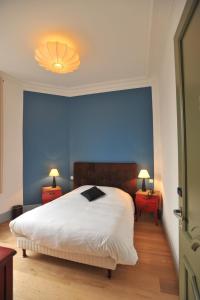 a bedroom with a large white bed and blue walls at Hotel Le Rayon Vert in Étretat