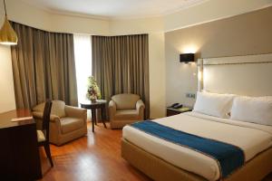 une chambre d'hôtel avec un lit et une chaise dans l'établissement Katriya Hotel and Tower, à Hyderabad