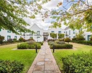 an exterior view of a white building with a garden at City Lodge Hotel GrandWest in Epping