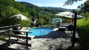a swimming pool with an umbrella and two chairs and a table at La Grange in Lautenbachzell