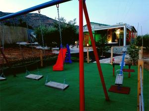 un parque infantil con columpios en un patio en Elaia Rest House Retreat in nature, en Fréngaina