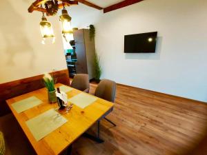 a dining room with a wooden table and a television at Burgbichl Apartments in Rothenthurn