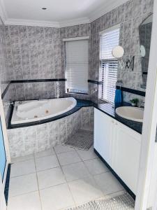 a bathroom with a bath tub and two sinks at Marionguesthouse in Ballito +55 photos