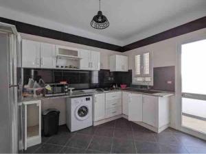 a kitchen with white cabinets and a dishwasher at Djerba apartments 2 in Bin Rhilouf