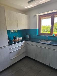 a kitchen with white cabinets and a sink and a window at Apartment Hügelruhe Mandach - 100 m2 - 3 Schlafzimmer - Ferien - Business in Böttstein