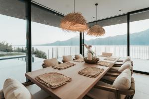 a dining room with a table and chairs and windows at LUXE VISTA Lakeside Villa Brenzone in Brenzone sul Garda