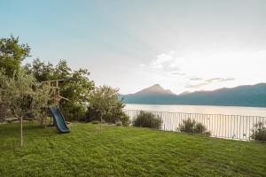 a playground with a slide next to a body of water at LUXE VISTA Lakeside Villa Brenzone in Brenzone sul Garda +48 photos