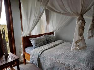 a bedroom with a canopy bed and a window at Villa Esa Bagus - Volcano view - big pool in Tampaksiring