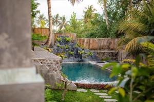 a swimming pool in a garden with a waterfall at Villa Esa Bagus - Volcano view - big pool in Tampaksiring +10 photos