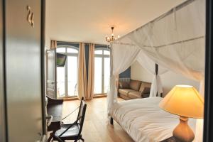 a bedroom with a canopy bed and a couch at Hotel Le Rayon Vert in Étretat