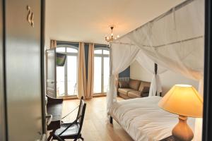 - une chambre avec un lit à baldaquin et un canapé dans l'établissement Hotel Le Rayon Vert, à Étretat